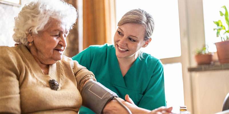 Caregiver taking elderly woman's blood pressure